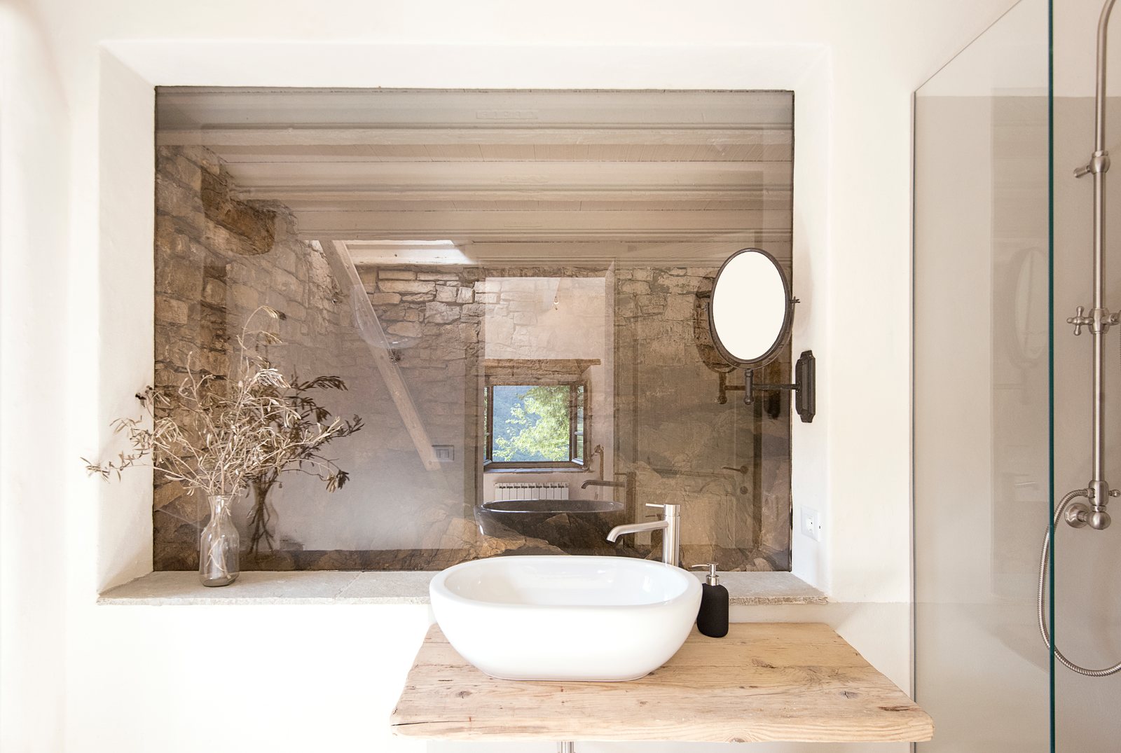 Bathroom with a vessel sink and an interior window onto a stone-walled room with a stone bathtub