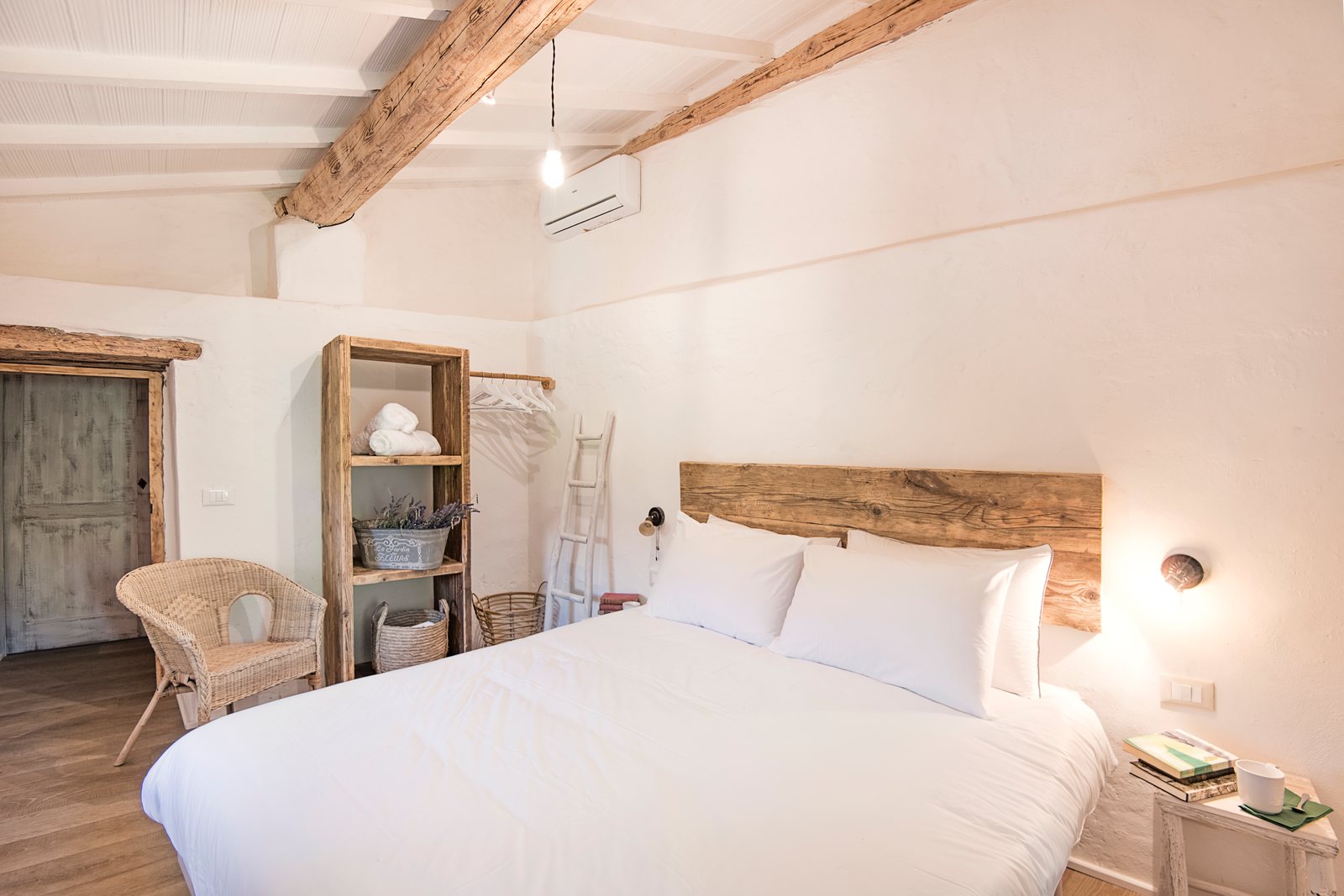 Double bedroom with a reclaimed wood headboard and a wicker armchair
