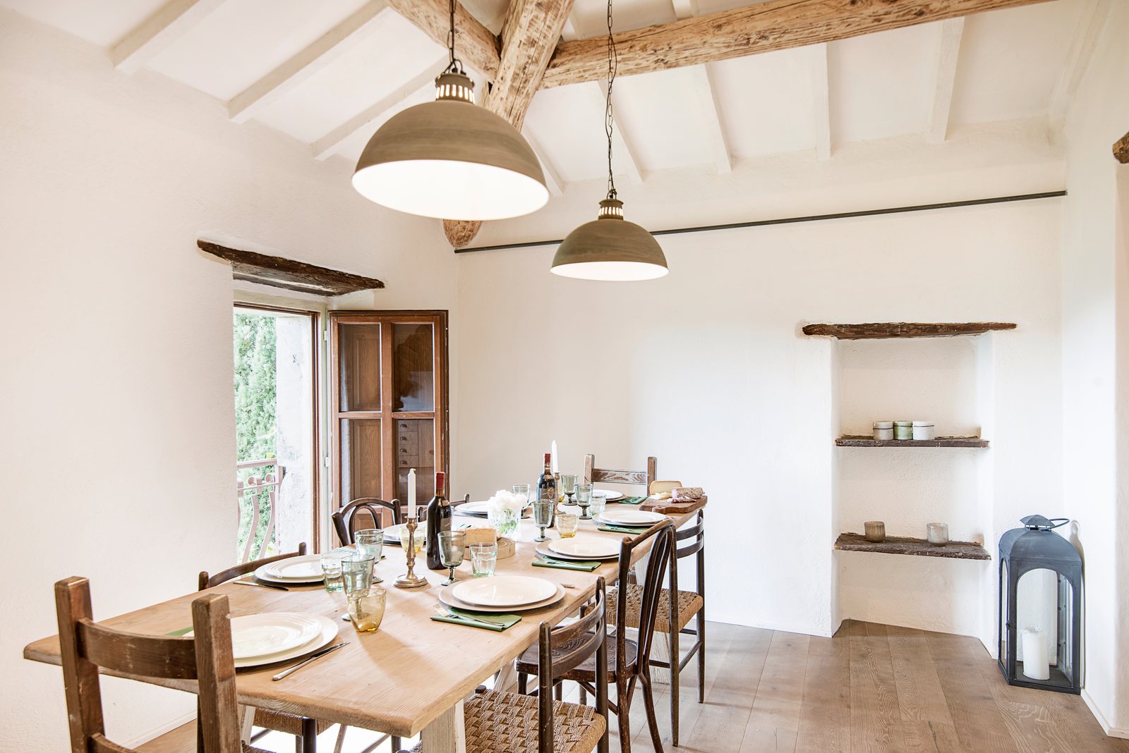 Dining room with a long wooden table, beamed ceiling and pendant lamps