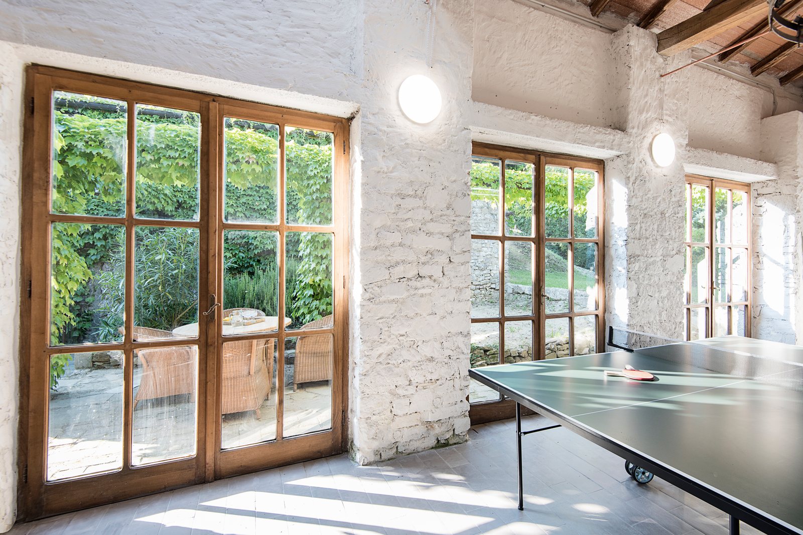 The studio games room, with a ping pong table and tall glass doors onto the ivy terrace